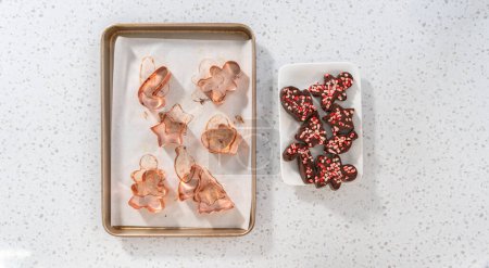 Photo for Flat lay. Removing freshly made Christmas cookie-cutter peppermint fudge from cookie cutters. - Royalty Free Image