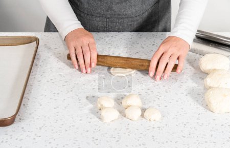Téléchargez les photos : Rouler la pâte à pain avec un rouleau à pâtisserie français pour cuire les trempettes naan. - en image libre de droit