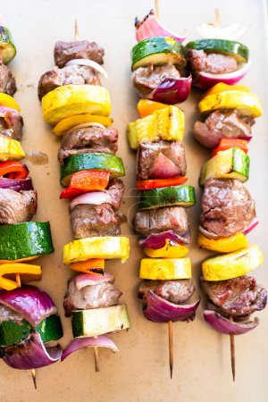 Téléchargez les photos : Brochettes de bœuf aromatisées et légumes colorés, marinées et grillées à la perfection, grillées sur une plaque à pâtisserie. - en image libre de droit