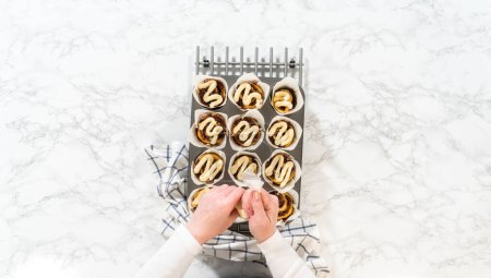 Photo for Flat lay. Garnishing no-yeast cinnamon roll cupcakes with cream cheese frosting from the piping bag. - Royalty Free Image