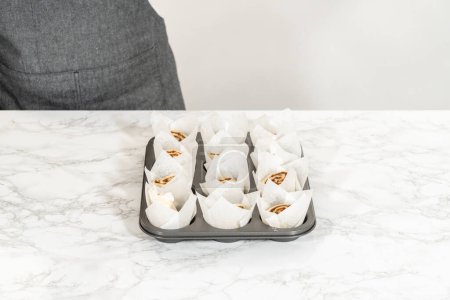 Téléchargez les photos : Remplir les garnitures de cupcake avec de petits rouleaux de cannelle pour cuire des cupcakes à la cannelle sans levure. - en image libre de droit