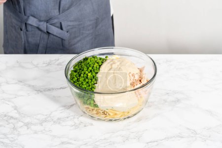 Téléchargez les photos : Mélanger les ingrédients dans un grand bol à mélanger en verre pour faire une salade de macaronis avec du poulet. - en image libre de droit