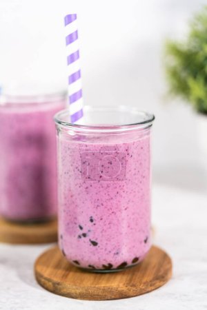 Foto de Freshly made mixed berry boba smoothie in a drinking jar with paper straw. - Imagen libre de derechos