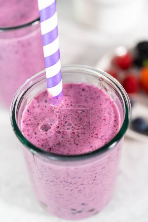 Foto de Freshly made mixed berry boba smoothie in a drinking jar with paper straw. - Imagen libre de derechos