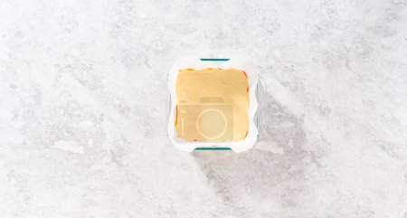 Téléchargez les photos : Pose plate. Verser le mélange de caramel dans le moule en verre carré doublé de papier parchemin pour préparer le caramel au maïs.. - en image libre de droit