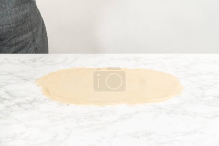 Photo for Rolling bread dough with a french rolling pin to bake bake no-yeast cinnamon roll cupcakes. - Royalty Free Image