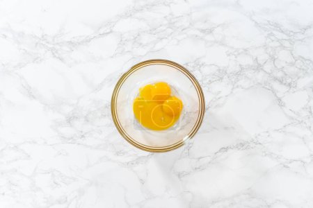 Téléchargez les photos : Pose plate. Biscuits au citron avec glaçage au citron. Mélanger les ingrédients humides dans un grand bol de mélange en verre pour cuire des biscuits au coin de citron. - en image libre de droit