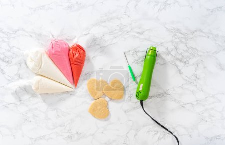 Foto de Acostado. Gelatina real casera en bolsas de tuberías listas para decorar galletas de azúcar en el mostrador de la cocina. - Imagen libre de derechos