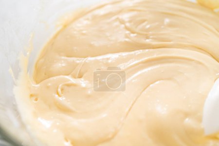 Photo for Melting chocolate chips and other ingredients in a glass mixing bowl over boiling water to prepare candy corn fudge. - Royalty Free Image