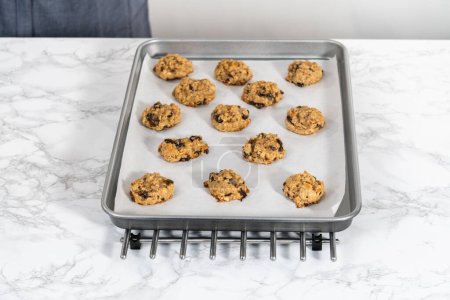 Photo for Cooling freshly baked soft oatmeal raisin walnut cookies on a kitchen counter. - Royalty Free Image