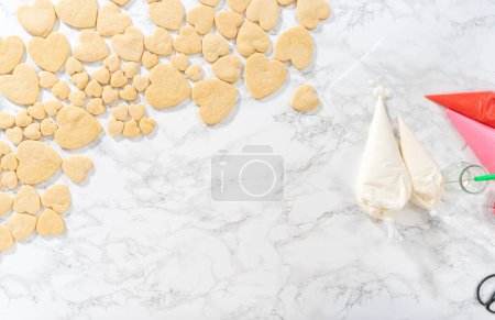 Téléchargez les photos : Pose plate. Décoration de biscuits au sucre en forme de cœur avec glaçage royal rose et blanc pour la Saint-Valentin. - en image libre de droit