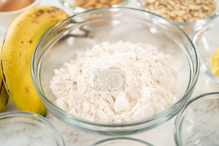 Téléchargez les photos : Ingrédients mesurés dans des bols à mélanger en verre pour cuire des muffins d'avoine de banane. - en image libre de droit
