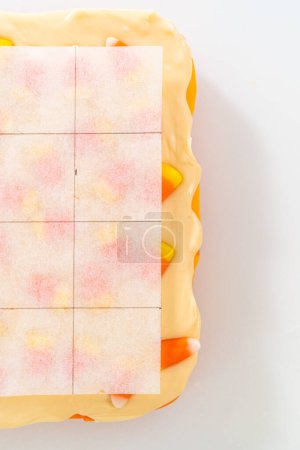 Photo for Scoring candy corn fudge using a parchment paper template for cutting into small pieces. - Royalty Free Image