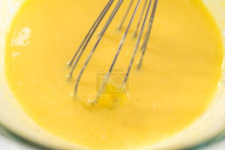 Photo for Mixing wet ingredients in a large glass mixing bowl to bake mini Easter bread kulich. - Royalty Free Image