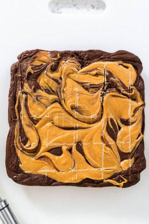 Photo for Scoring chocolate fudge with peanut butter swirl for cutting into small pieces. - Royalty Free Image