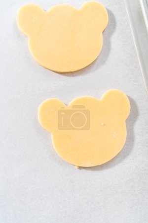 Photo for Rolling cookie dough and cutting out panda-shaped shortbread cookies. - Royalty Free Image