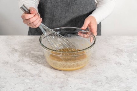 Photo for Mixing wet ingredients in a small glass mixing bowl to bake banana cookies with chocolate drizzle. - Royalty Free Image