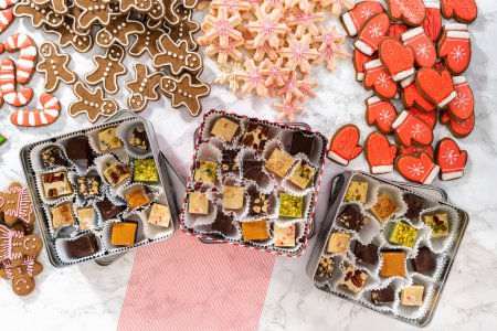 Téléchargez les photos : Pose plate. Emballage d'une variété maison de biscuits au caramel et au pain d'épice pour les cadeaux alimentaires de Noël dans des boîtes d'étain. - en image libre de droit