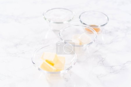 Téléchargez les photos : Ingrédients mesurés dans un bol de mélange en verre pour préparer la sauce à la bruine de fromage à la crème. - en image libre de droit