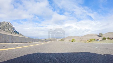 Téléchargez les photos : Par une belle journée d'hiver, une voiture parcourt l'emblématique Highway 101 près de San Luis Obispo, en Californie. Le paysage environnant est brunâtre et tamisé, avec des collines ondulantes et des zones côtières - en image libre de droit
