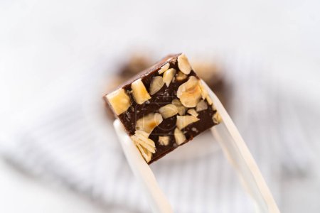 Foto de La celebración de chocolate casero avellana fudge pieza cuadrada con pinzas de cocina. - Imagen libre de derechos