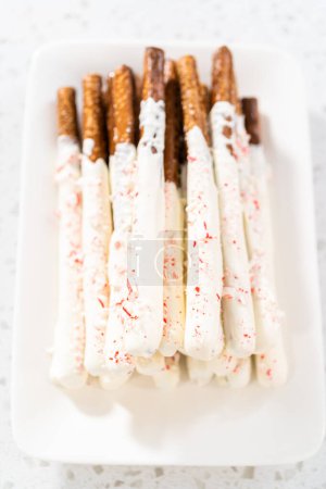 Téléchargez les photos : Pile de tiges de bretzel recouvertes de chocolat de canne à sucre maison sur une assiette de service blanche. - en image libre de droit