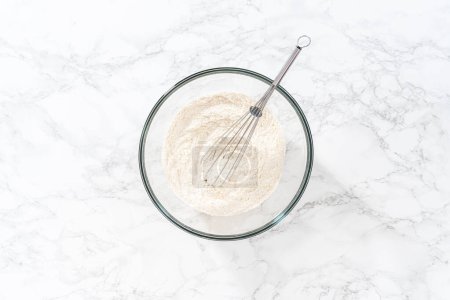 Téléchargez les photos : Flat lay. Mixing dry ingredients with a hand whisk in a large glass mixing bowl to bake American flag mini cupcakes. - en image libre de droit