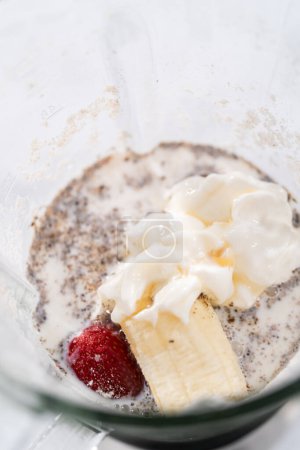 Photo for Blending ingredients for healthy breakfast strawberry banana smoothie in a kitchen blender. - Royalty Free Image
