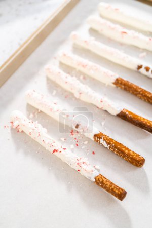 Hausgemachte Zuckerrohrschokolade überzogene Brezelstangen trocknen auf einem Backblech, das mit Pergamentpapier ausgekleidet ist.