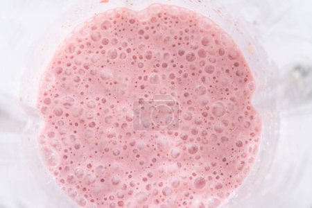 Téléchargez les photos : Mélange d'ingrédients pour un petit déjeuner sain smoothie banane fraise dans un mélangeur de cuisine. - en image libre de droit