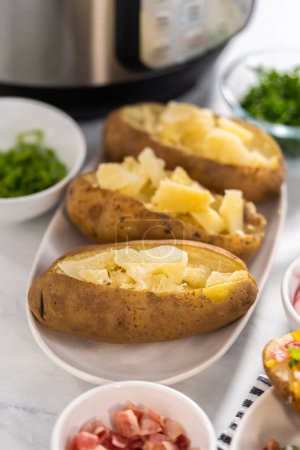 Téléchargez les photos : Pommes de terre cuites au four Pressure Cooker. Trancher les pommes de terre entières cuites sur une assiette blanche pour faire des pommes de terre cuites au four. - en image libre de droit