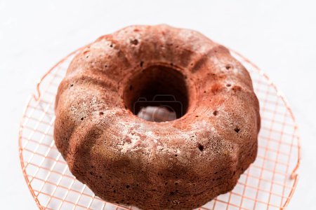 Téléchargez les photos : Refroidissement gâteau bundt en velours rouge fraîchement cuit sur un comptoir de cuisine. - en image libre de droit