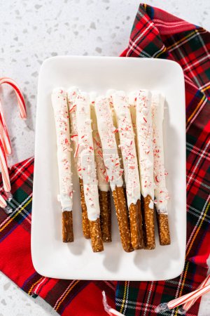 Photo for Pile of homemade candy cane chocolate-covered pretzel rods on a white serving plate. - Royalty Free Image