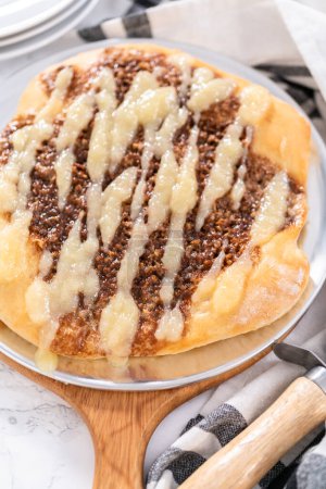 Téléchargez les photos : Pizza dessert à la cannelle fraîchement cuite avec un filet de fromage à la crème. - en image libre de droit