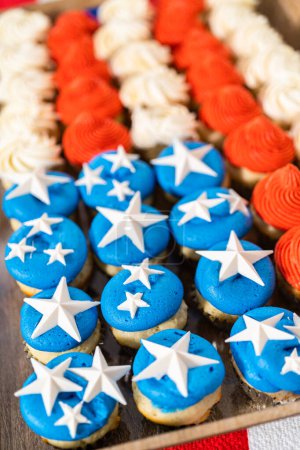 Foto de Arranging mini vanilla cupcakes in the shape of the American flag. - Imagen libre de derechos