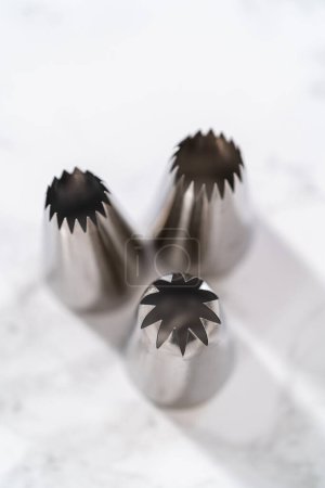 Foto de Punta de metal de tuberías Jumbo con una bolsa de tuberías en un mostrador de cocina para heladas cupcakes. - Imagen libre de derechos