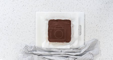 Téléchargez les photos : Flat lay. Cutting plain homemade fudge into small pieces on a white cutting board. - en image libre de droit