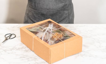 Foto de Caja de charcutería con carne en rodajas, queso, galletas y uvas, todo perfectamente empaquetado en una caja de regalo marrón. - Imagen libre de derechos
