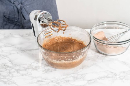 Foto de Mezclar ingredientes húmedos en un tazón de vidrio grande para hornear cupcakes de terciopelo rojo con glaseado de ganache de chocolate blanco. - Imagen libre de derechos