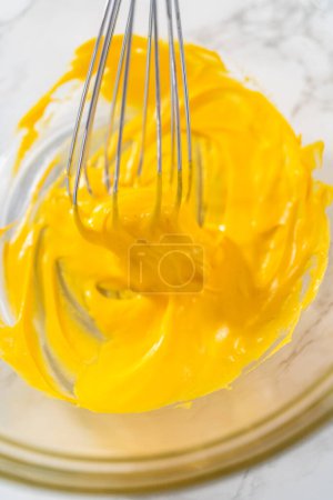 Foto de Mezcla de colorante de alimentos amarillos en el merengue para hornear galletas de merengue de Pascua. - Imagen libre de derechos