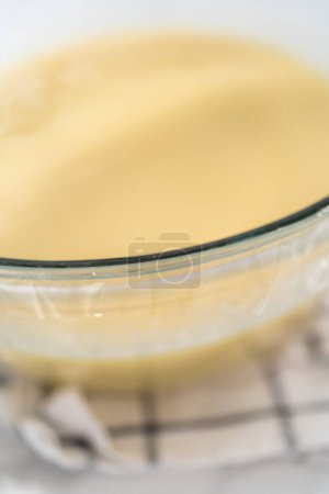 Téléchargez les photos : Fouetter dans un grand bol en verre avec les ingrédients pour faire le glaçage ganache chocolat blanc. - en image libre de droit