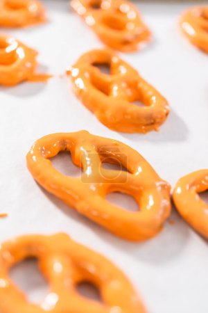 Foto de Sumergiendo pretzels tuerce en chocolate derretido para hacer giros de pretzel cubiertos de chocolate. - Imagen libre de derechos