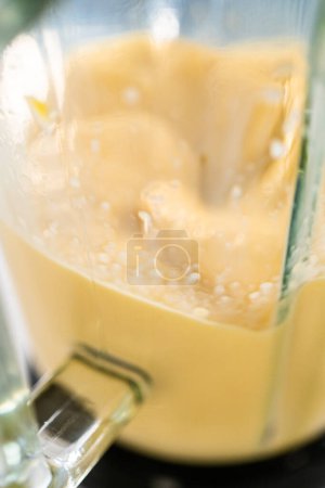 Téléchargez les photos : Mélange d'ingrédients dans un mélangeur de cuisine pour préparer un smoothie à la mangue et au boba. - en image libre de droit