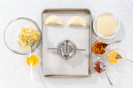 Téléchargez les photos : Pose plate. Remplir la pâte empanada avec du remplissage d'œufs pour faire des empanadas petit déjeuner avec des œufs et des patates douces. - en image libre de droit