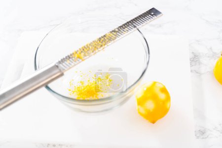 Téléchargez les photos : Zesting et jus de citron frais sur une planche à découper blanche. - en image libre de droit