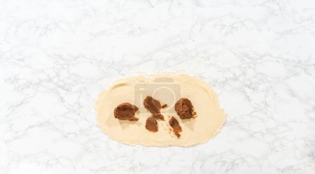 Photo for Flat lay. Filling rolled bread dough with cinnamon filling and chopped pecans to bake no-yeast cinnamon roll cupcakes. - Royalty Free Image