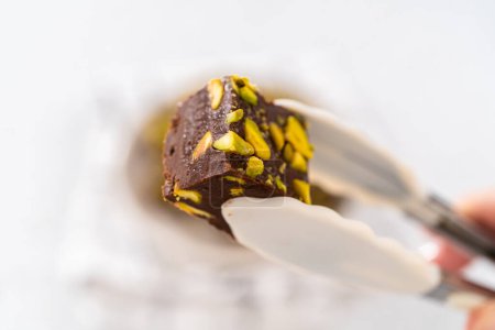 Foto de La celebración de chocolate casero pistacho fudge pieza cuadrada con pinzas de cocina. - Imagen libre de derechos