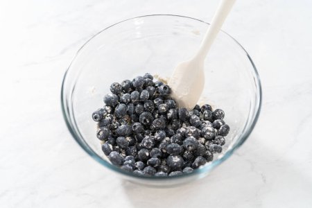 Photo for Coating fresh blueberries with all-purpose flour for baking. - Royalty Free Image