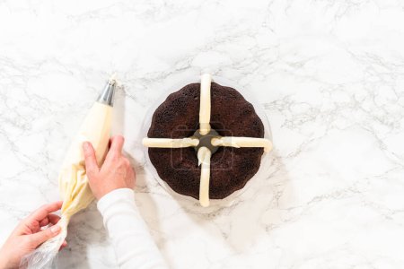 Téléchargez les photos : Pose plate. Avec précision, le gâteau au chocolat Bundt est soigneusement retiré de la casserole orné de glaçage au fromage à la crème luxuriant, créant un régal délicieux qui ravira certainement. - en image libre de droit