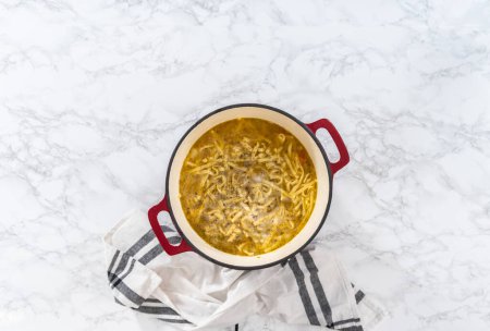 Photo for Flat lay. Cooking chicken noodle soup with kluski noodles in an enameled dutch oven. - Royalty Free Image